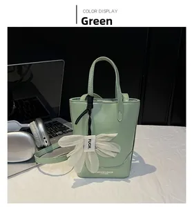 Detailed view of a light green tote bag with a white flower charm and adjustable strap