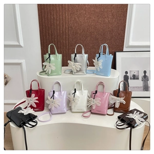 Collection of colorful mini PU leather tote bags with floral charms displayed on stands