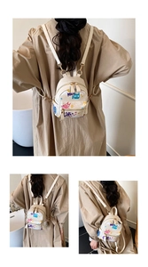 Detailed back view of a mini beige backpack with cute cat graffiti on a model
