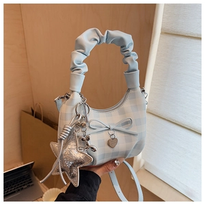 Detail of light blue checkered handbag with ruffle handle and heart charm accents