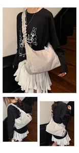Detail view of the beige canvas bag with ruffle shoulder strap and drawstring sides