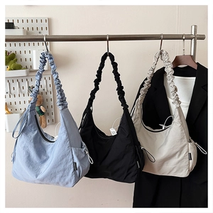 Detailed view of ruffled shoulder straps on three nylon bags in blue, black, and beige