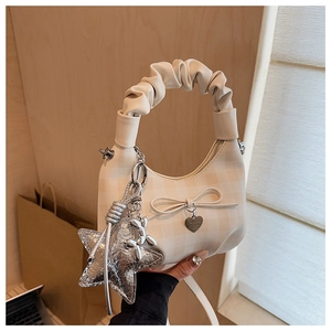 Detail of cream plaid handbag featuring ruffled handle and silver star bag charm