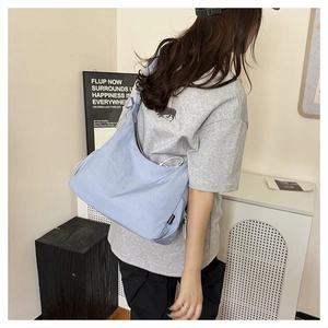 Detail view of light blue crescent tote bag in nylon fabric worn by a female model