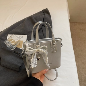 Detailed macro of silver textured bucket bag with pearl lace bow and metal handles