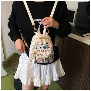 Detail of a mini cream backpack with colorful cartoon graffiti and gold zipper accents