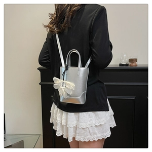 Detail of silver metallic tote bag with white tulle bow charm and shoulder strap
