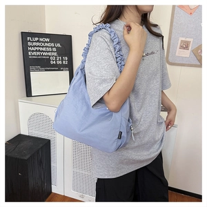 Detail of light purple pleated shoulder bag with ruffled strap worn by a female model
