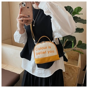 Close-up of yellow and white canvas crossbody bag featuring the Colour is belief text print