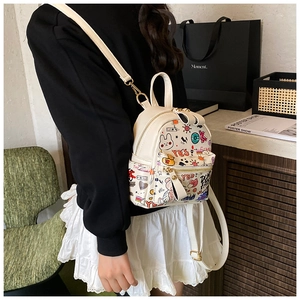 Close-up of doodle pattern backpack with gold zippers shown on a cross-body model