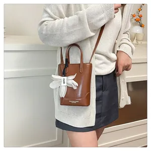 Close-up of brown leather tote bag with white flower charm and adjustable shoulder strap