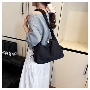 Detail view of black pleated nylon tote bag with pearl drawstring and half-moon shape