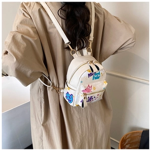 Close-up of white PU leather mini backpack with colorful cat graffiti and golden zippers