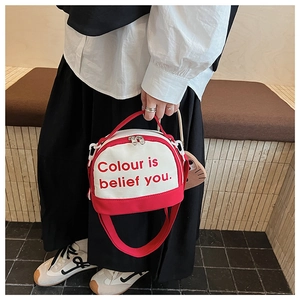 Detail of red and white canvas bag with printed slogan and cute cat keychain accessory