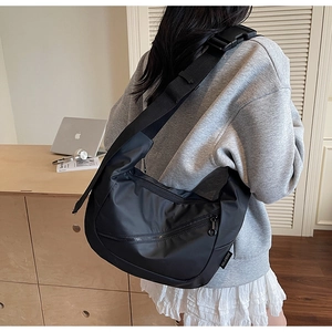 Detail of black nylon dumpling crossbody bag with adjustable strap and wide plastic buckle