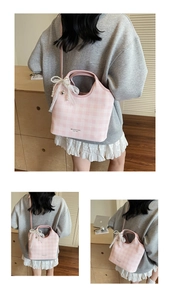 Détail du sac bandoulière à carreaux roses avec nœud en dentelle et pendentif en perle
