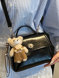 Chic black glossy crossbody bag with gold buckle and cute plush bear charm for women