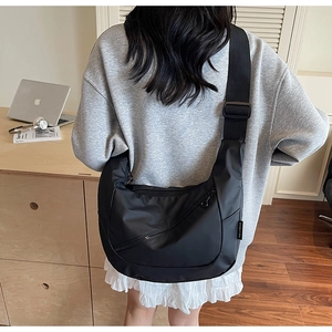 Detail of a large black nylon dumpling bag with adjustable strap and zip pocket
