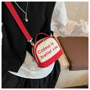 Detail of red and white canvas crossbody bag with wide strap and designer lettering