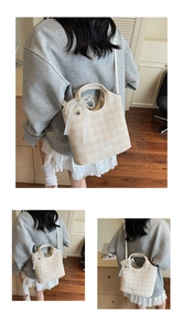 Détail du sac à carreaux avec nœud en dentelle délicate et breloque cœur en perles