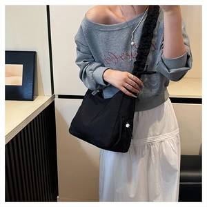 Detail of black pleated crossbody bag featuring side drawstring adjustment and nylon texture