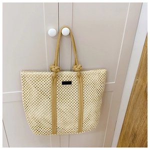 Detail of summer woven tote bag featuring soft straw texture and black square patch