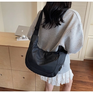 Detail of adjustable wide shoulder strap and water-resistant nylon material on black crossbody bag
