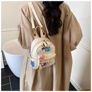 Mini cream backpack with cartoon graffiti and gold hardware shown on a model back