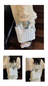 Détail du sac à carreaux bleu clair avec nœud en dentelle blanche et pendentif perle