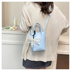 Close-up of light blue mini tote bag featuring white organza flower charm and strap