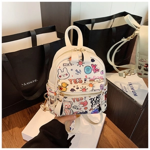 Detailed close-up of white mini backpack with colorful graffiti prints and metal zipper