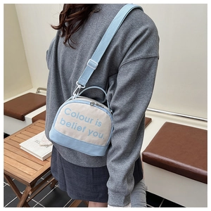 Detail of the blue and white canvas crossbody bag with slogan and adjustable strap