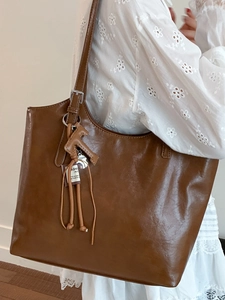 Minimalist large brown leather tote bag with horse pendant charm and shoulder strap