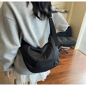 Close-up of black nylon dumpling bag with adjustable wide strap and zip pocket detail