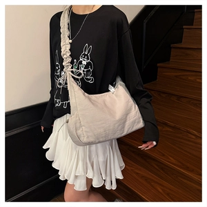 Detailed view of cream-white pleated shoulder strap bag worn with casual street style outfit