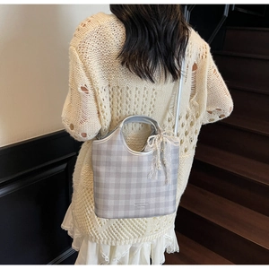 Gros plan d'un sac à damier argenté avec nœud en dentelle perlée sur les escaliers
