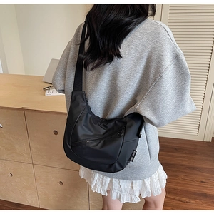 Lifestyle shot of black nylon crescent crossbody bag with branded label and wide strap