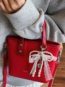 Red bucket bag for women with lace pearl bow charm and shoulder strap in lifestyle setting
