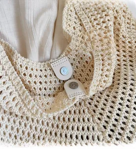 Detail of cream crochet handbag featuring intricate hollow knit patterns and premium metal clasp