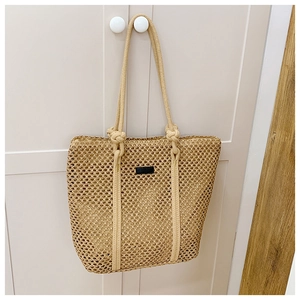 Detail of beige woven tote bag showing knotted rope handles and mesh texture