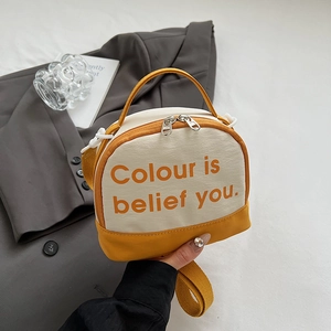 Detail of a yellow and beige half-round canvas crossbody bag with top handle and strap