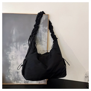 Detail of black scrunchie shoulder strap and nylon fabric on minimalist hobo bag