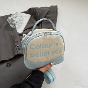 Detailed close-up of blue and white canvas crossbody bag with top handle and metal zipper