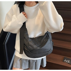 Model wearing a black nylon crescent bag with adjustable wide strap and outer zipper