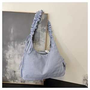 Detail of light blue pleated nylon crossbody bag with drawstring side and silver zipper