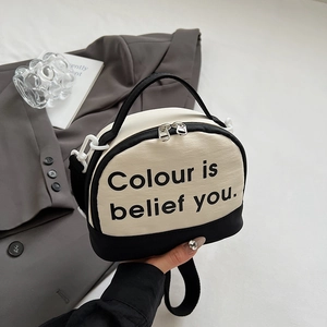 Detail of black and white handbag with letter print on gray suit and books background