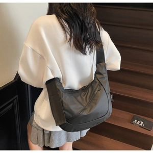 Side view of a large black nylon crossbody crescent bag on a model in urban style