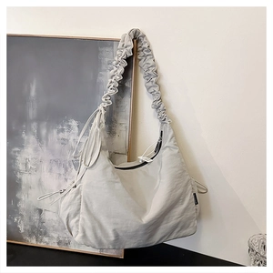 Detail of light gray tote bag featuring unique pleated cloud-style shoulder strap design