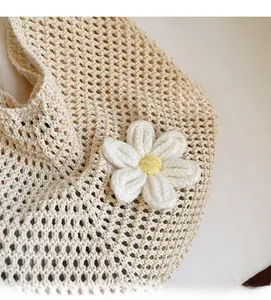 Close-up of cream knit tote bag showing hollow crochet mesh and white floral detail