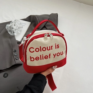 Detail view of mini canvas crossbody bag in red and white with silver dual zippers